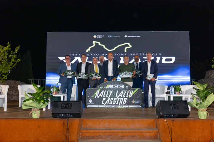Foto di gruppo sul palco con scenografia del Rally